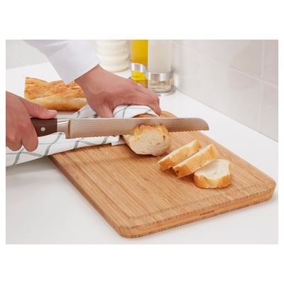 Person som skär bröd med en vass, hållbar kniv på en skärbräda av trä.