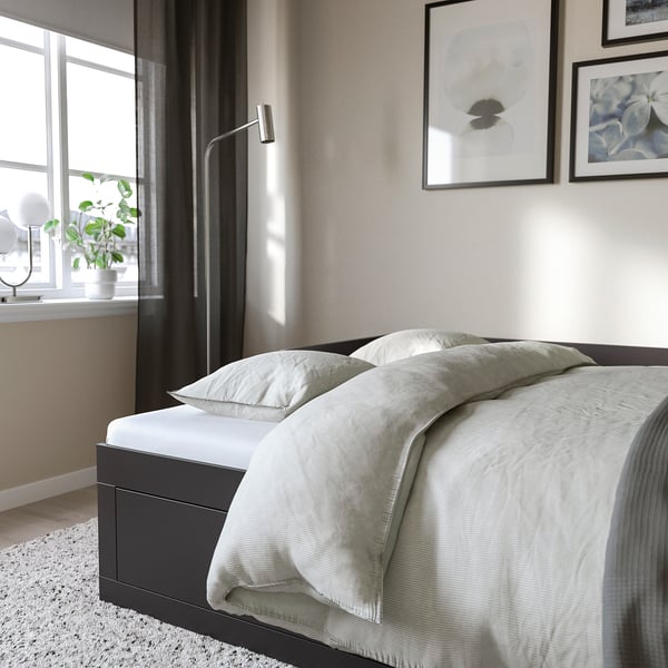 En modern säng med stora förvaringslådor under. Sängen har en ren design, perfekt för små utrymmen.