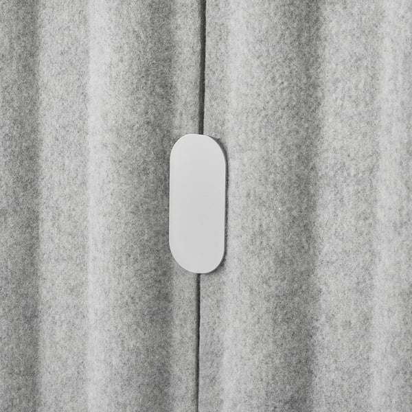 Oval vit knapp på grå texturerad yta.