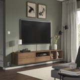 Modernt vardagsrum med gröna väggar, platt-tv, träkonsol med inredning, fönster med gardiner och grå stol.