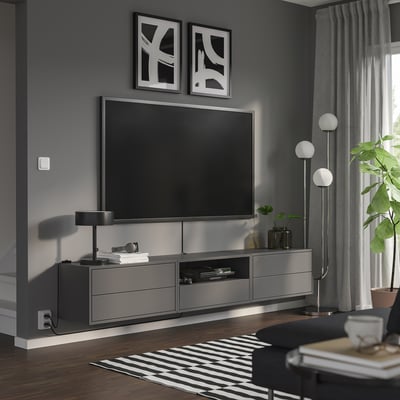 Modernt vardagsrum med elegant, grå EKET tv-enhet, plattskärms-tv, snygga lampor och växter; Minimalistisk inredning.