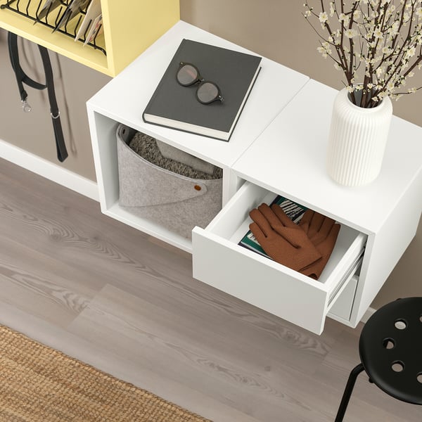 Vägghängt skåp med öppen och stängd förvaring; Grå korg, låda med kläder.