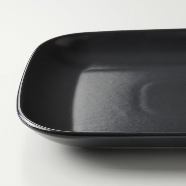 Slät, blank svart stengodsplatta, runda kanter, modern design.