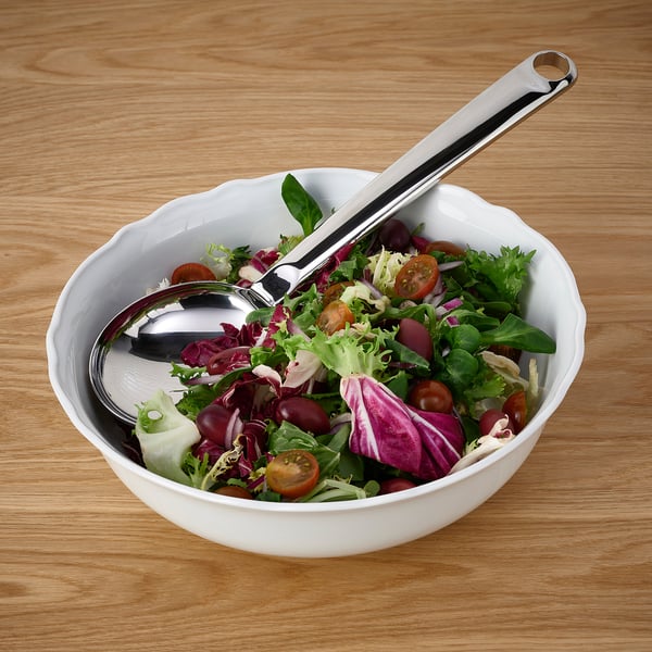 En skål med sallad med FINMAT-sked som vilar på ett träbord, redo att serveras.