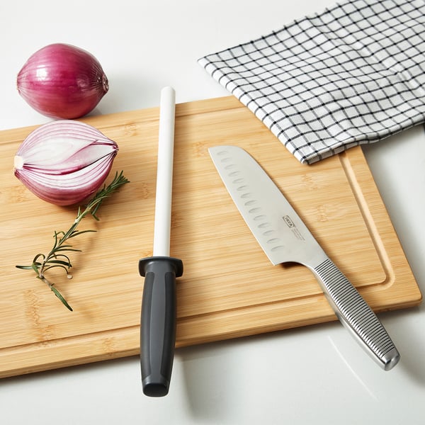 Skärbräda i bambu med knivslip, kniv, lök, rosmarin.