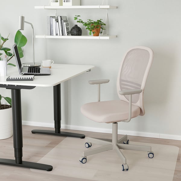 Vit IKEA FLINTAN kontorsstol med rygg i mesh, bredvid skrivbordet med laptop, kompakt och ergonomisk för långa arbetstimmar.