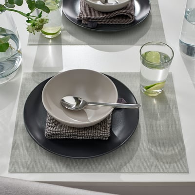 Bordsduk med FLYGFISK bordstabletter, skål och sked, glas vatten med limeskiva.