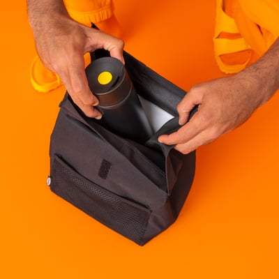 Person som lägger svart isolerad matsäck i orange påse.