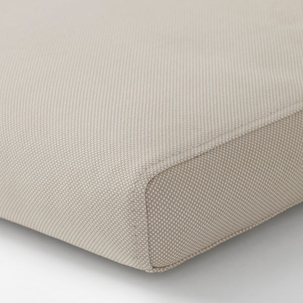 Närbild på ett beige, texturerat kuddfodral med dragkedja, tillverkat av återvunnet material.