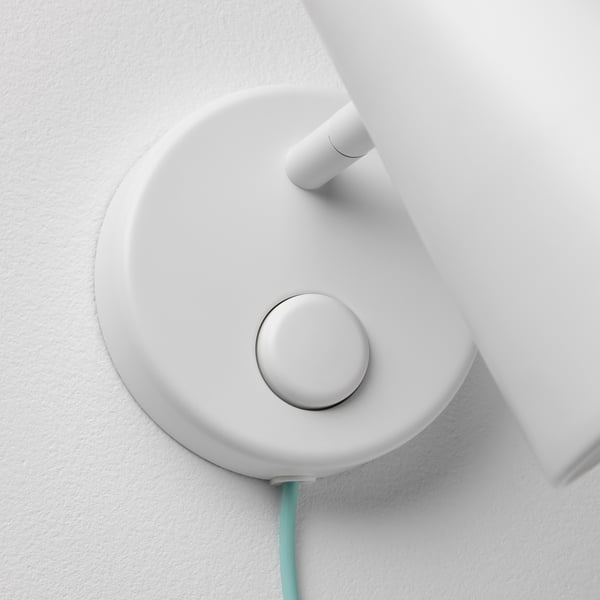 Modern dimbar vägglampa med elegant vit design och rund knapp, fäst på väggen.