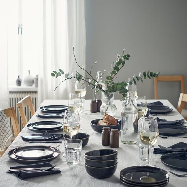 Elegant matbordsset med tallrikar, glas, duk och eukalyptus i centrum.