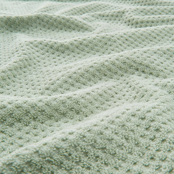 Mjuk, fluffig beige handduk i närbild som visar den tjocka, strukturerade bomullsväven.