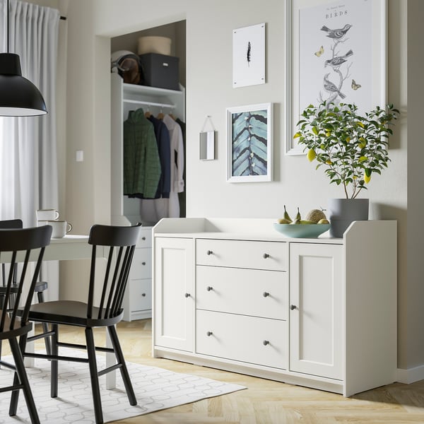 Moderna, vita HAUGA sideboardlådor och skåp som visar upp en elegant design med dekorativa föremål och grönska på toppen.