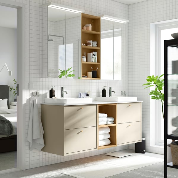 Modern badrum med HAVBÄCK beige handfat, dubbla handfat, ljusa trähyllor och stor spegel. Handdukar och växter ger dekoration.