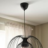 Från taket hänger en modern pendellampa med intrikat, vävd design och ger justerbar belysning.