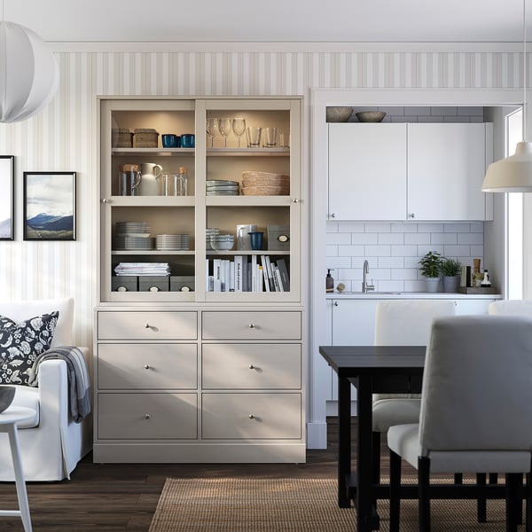 Beige furu HAVSTA enhet med glas och trä; Visar glas, porslin. Vitt kök, grå stol.
