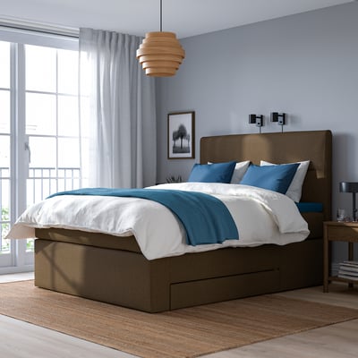 Modernt sovrum med brun säng HEMFJÄLLET , blå accenter, stort fönster, taklampa, förvaring under sängen och beige matta.