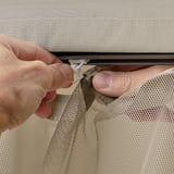 Händer som installerar nät på HIMMELSÖ lusthus för ventilation.