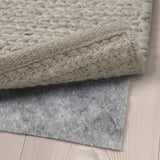 Närbild på HJORTSVANG ullmattor, vävd textur och fäst filt halkskyddsmatta.