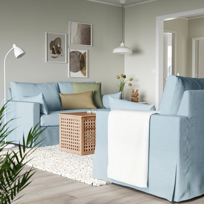 Modernt vardagsrum med ljusblå l-formad HYLTARP soffa, soffbord i ljust trä och väggkonst. Soffan är stor, passar hörn bra.