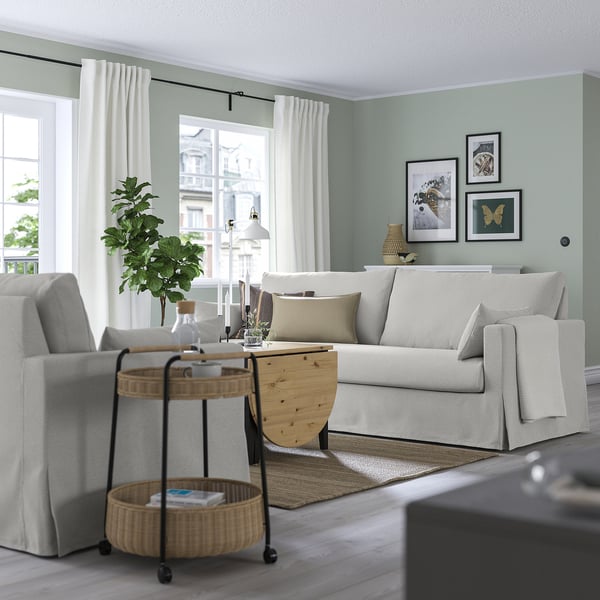 Vardagsrum med HYLTARP soffa, fönster, sidobord, gröna väggar, konst