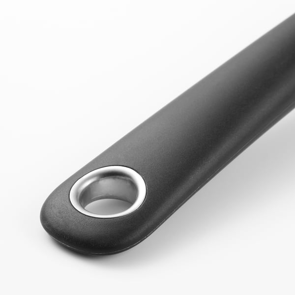 Svart köksredskap med metalliska cirkulära detaljer, designade för hållbarhet och grepp.