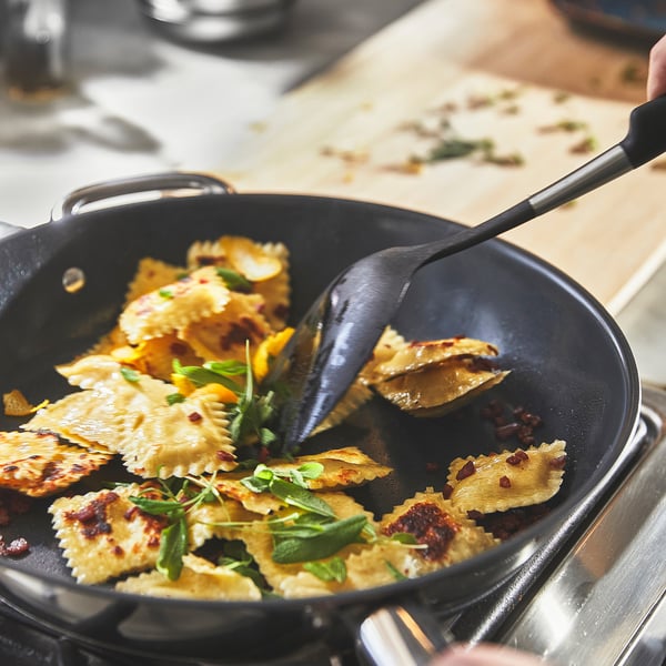 Svart stekpanna med ravioli, non-stick, lätt att röra, två handtag.