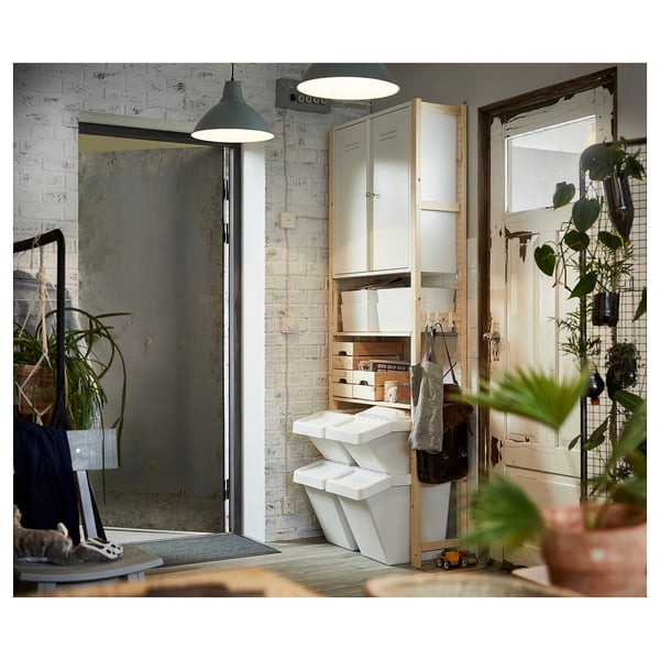 Ett IVAR-förråd i ett rum med vitmålade tegelväggar. Den har flera hyllor och lådor av naturlig furu och rymmer olika föremål.