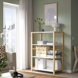 IVAR förvaringsenhet med böcker och lådor, högre än soffbordet, nära den prickiga soffan.