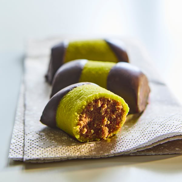 Gröna och bruna cylindriska kakor med kakao slutar på en vit servett.