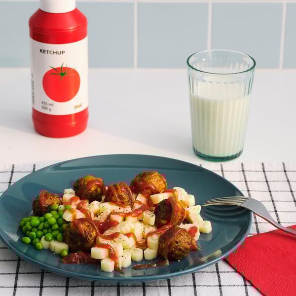 En måltid med ärtor, potatis, korv, KETCHUP, mjölk, på en rutig duk.