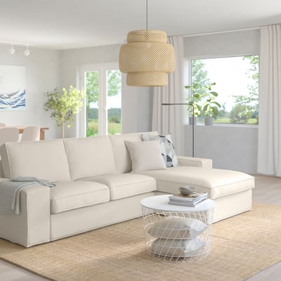 Modernt vardagsrum med KIVIK cremefärgad soffa, vitt soffbord, neutral inredning, stora fönster och beige matta.