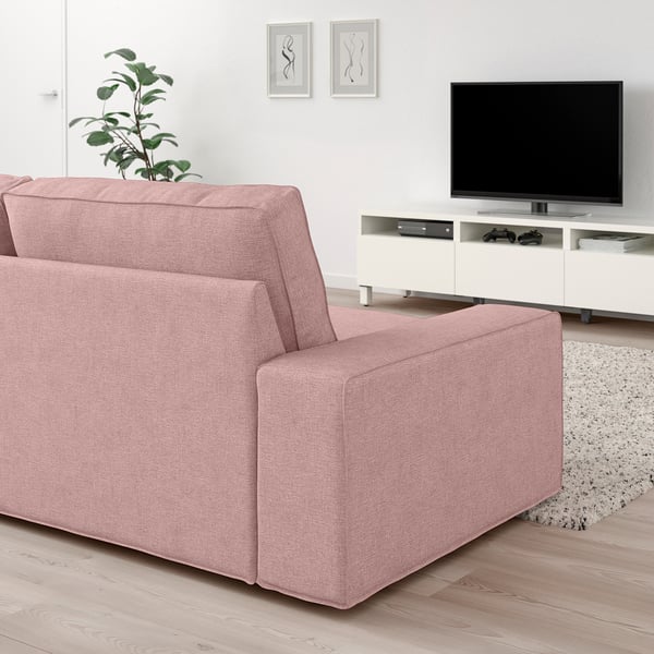 Modern rosa KIVIK soffa med låga armstöd, stora kuddar och en vit tv-bänk i ett minimalistiskt vardagsrum.