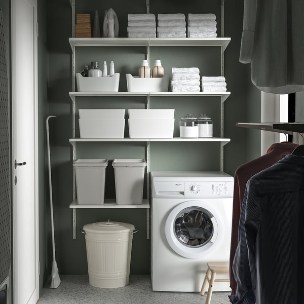 Tvättstuga med KNODD soptunna, vikta handdukar, städartiklar och tvättmaskin.