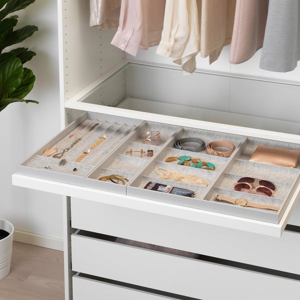 En utdragbar låda organiserar smycken och accessoarer i filtfodrade fack, en del av ett modernt garderobssystem.