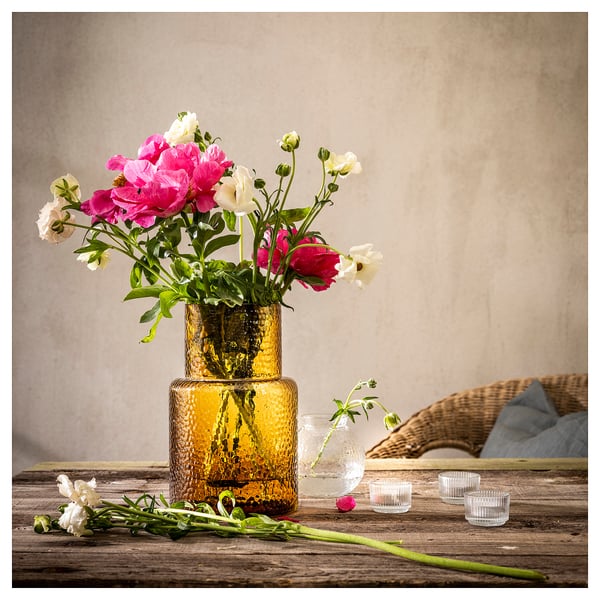 KONSTFULL gul vas med rosa och vita blommor på rustikt bord.