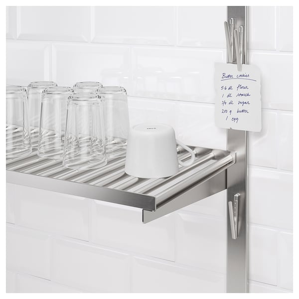 Metallhylla i köket med glas, kopp och receptanteckning klippt magnetiskt.