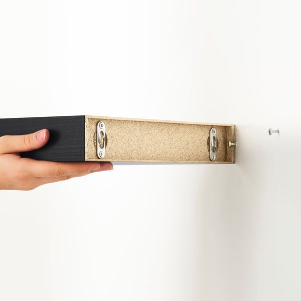 Håll LACK vägghylla för hand, som visar dolda monteringsfästen. Kompakt, platsbesparande design.