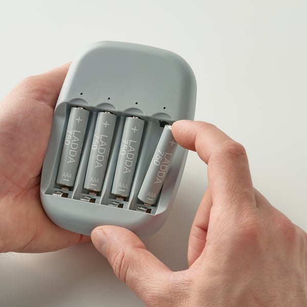 Händer som håller LADDA laddare med 4 aaa-batterier redo att användas.