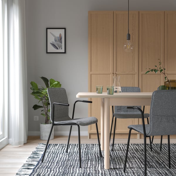 Modern matgrupp med träskåp, bord, grå LÄKTARE-stolar, glödlampa, växt och mönstrad matta.