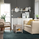 Modernt vardagsrum med LANDBANA jutematta, två fåtöljer, soffa och inredning på grå vägghyllor som skapar en mysig atmosfär.