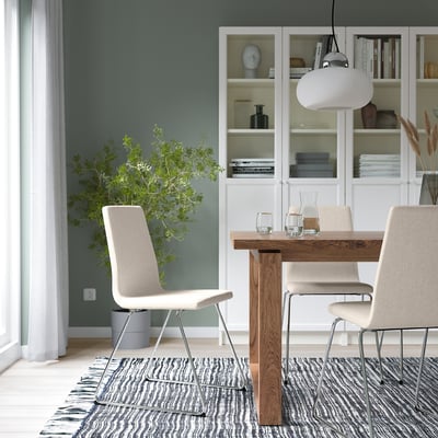 Modern matplats med beige stol LILLÅNÄS, träbord, vit taklampa, grå matta och bokhylla med blå vas.