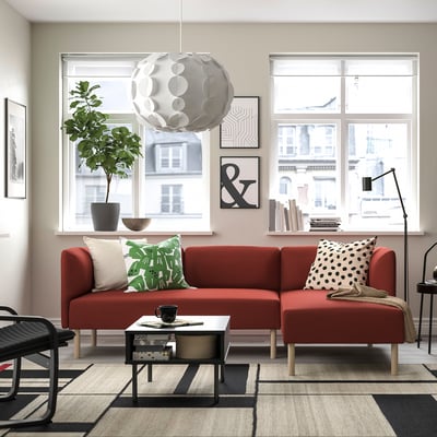 Modernt vardagsrum med röd soffa LILLEHEM, stora fönster, växt och svart soffbord.