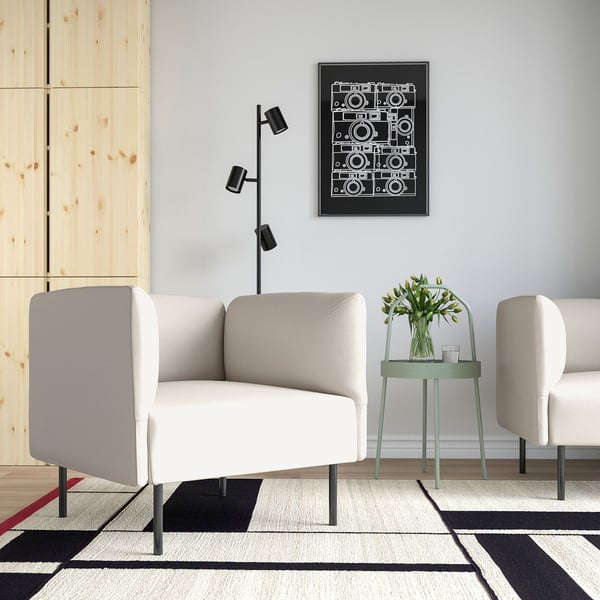 Modernt vardagsrum med en vit LILLEHEM soffa och sidobord. Dekorerad med en geometrisk matta, ett konstverk och en grön pall med blommor.