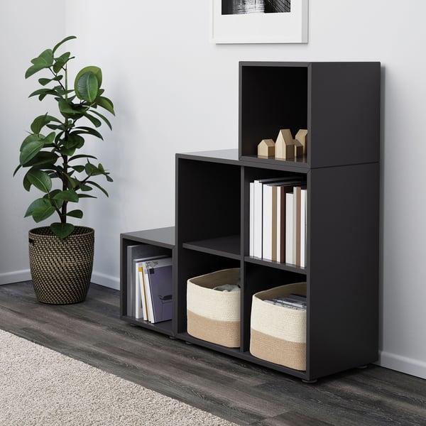 Modernt rum med mörkgrå LJUNGAN kubförvaring, stora korgar, böcker, växter, vit väggkonst, grå och vit matta.