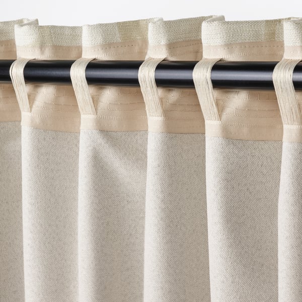 Gardinnärbild: beige jacquard block-out-paneler med huvudkrokar, stylade för ljuskontroll.