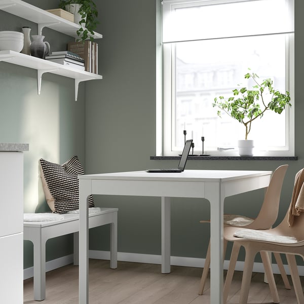 Mysig arbetsplats med skrivbord, bärbar dator, växt, ljus, stol, gröna väggar, bokhylla.