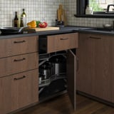 Kökshörnskåp i trä med utdragbara hyllor för stora kastruller, med justerbara gångjärn och en mörk yta.