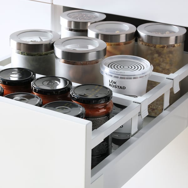 Organiserad kökslåda med genomskinliga burkar och behållare som visar lagrade livsmedel och ingredienser.