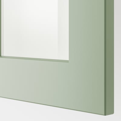 Närbild på en modern grön inramad vitrinskåpsdörr från ikeas METOD kökssystem, som visar upp sin eleganta, robusta design.